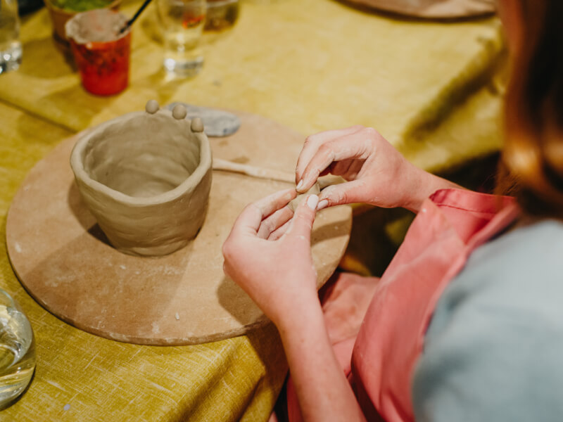 A woman rolling homemade clay into a small ball.